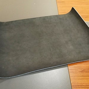 Pode incluir: Um tapete de rato retangular de tecido cinzento escuro com uma borda ligeiramente curva.