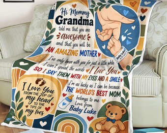 May include: A soft throw blanket featuring a printed design with text reading Hi Mommy Grandma told me that you are awesome and that you will be AN AMAZING MOTHER, along with illustrations of a baby hand holding an adult finger, a teddy bear, a baby bottle, and rainbows.