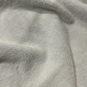 May include: Close-up of a white, soft, fluffy fabric with a slightly textured surface.