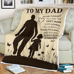 May include: A beige and brown fleece blanket with a silhouette of a father and daughter walking. The blanket has the text "To My Dad" and a message about being the first man loved and always being number one.