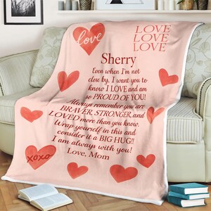 May include: A pale pink blanket featuring red hearts and the words "Love, Love, Love" and "Sherry". The blanket has a message from "Mom" with the words "xoxo" on it.