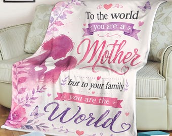 May include: A white blanket with a pink and purple floral design and the words "To the world you are a Mother but to your family you are the World" in pink and purple script. The blanket features a silhouette of a mother and child.