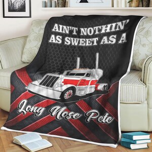 May include: A black and red fleece blanket with a white semi-truck and the text "Ain't nothin' as sweet as a Long Nose Pete".