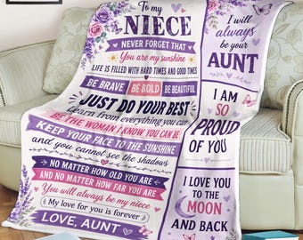 May include: A white fleece blanket featuring purple floral accents, butterflies, and printed text addressed to a niece from an aunt. The design includes motivational phrases, hearts, and the message I love you to the moon and back in purple lettering.