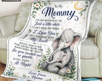 May include: A white fleece blanket featuring a graphic of a mother elephant cuddling a baby elephant, decorated with green leaves, small flowers, and a yellow crescent moon. The text reads: To My Mommy, I've only been with you for just a little while.