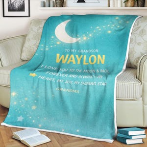 Peut inclure: Une couverture turquoise avec un croissant de lune blanc et des étoiles dorées. Le texte dit : "À mon petit-fils Waylon, je t'aime jusqu'à la lune et retour, pour toujours et à jamais - mon cœur, ma joie, mon étoile brillante, Grand-mère."