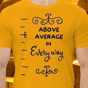 Peut inclure: Un t-shirt jaune avec un motif noir qui dit "Above Average in Every Way". Le motif est une règle avec une ligne qui s'étend au-dessus du haut de la règle.