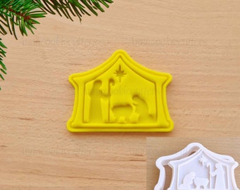 Puede incluir: Cortador de galletas de plástico amarillo en forma de portal de Belén con una estrella en la parte superior. El cortador está sobre una superficie de madera.