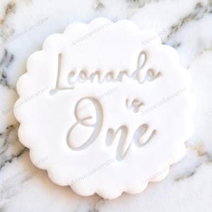 Può includere: Un tagliabiscotti bianco con bordo smerlato con le parole "Leonardo is One" in corsivo. Il testo è ritagliato dal tagliabiscotti. Il prodotto è progettato per fare biscotti.