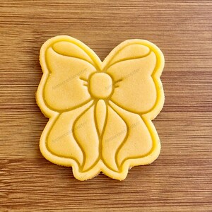 Può includere: Un biscotto di zucchero giallo a forma di fiocco. Il biscotto ha un design dettagliato ed è pronto per essere decorato.