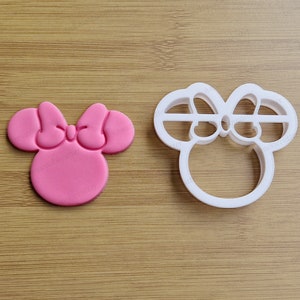 Può includere: Un tagliapasta rosa e un tagliapasta di plastica bianca, entrambi a forma di testa di topo dei cartoni animati con un fiocco.