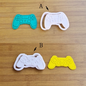 Può includere: Tre stampini per biscotti in plastica a forma di controller per videogiochi. Gli stampini sono bianchi, verdi e gialli.