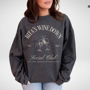 a woman wearing a sweatshirt with a wine glass on it