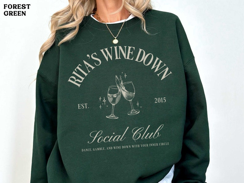 a woman wearing a green sweatshirt with a picture of two glasses of wine on it