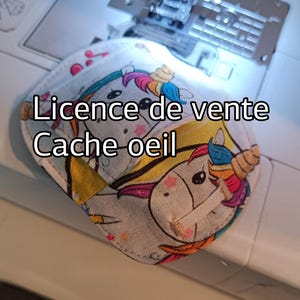 Peut inclure: Un masque pour les yeux blanc avec un motif de licorne. Le masque a une crinière et une corne arc-en-ciel, et le texte "Licence de vente Cache oeil" est imprimé sur le devant.