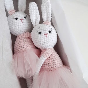 Puede incluir: Dos mu&ntilde;ecas de conejo de crochet blanco con tut&uacute;s rosas. Los conejos tienen ojos negros y narices rosas. Est&aacute;n sentados en una caja blanca.