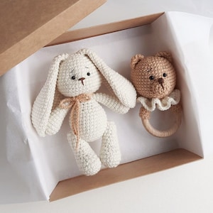May include: A white crocheted bunny and a brown crocheted bear rattle in a brown gift box with white tissue paper.