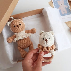 Puede incluir: Dos osos de peluche tejidos a crochet, uno marr&oacute;n y otro blanco, en una caja de regalo. El oso blanco est&aacute; unido a un anillo de dentici&oacute;n de madera.