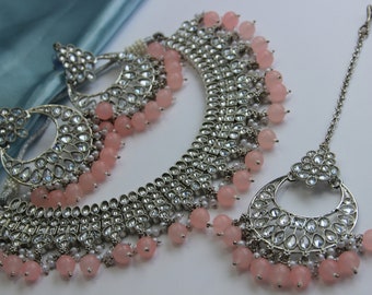 May include: A silver and pink jewelry set with a necklace, earrings, and a nose ring. The necklace and earrings feature a silver design with clear stones and pink beads. The nose ring is a silver hoop with a clear stone design.