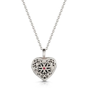 May include: A silver heart-shaped locket necklace with a delicate filigree design and a small red gemstone in the centre.