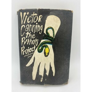 May include: A black and white book cover with the title "Victor Canning The Python Project" and a green snake wrapped around a white hand.