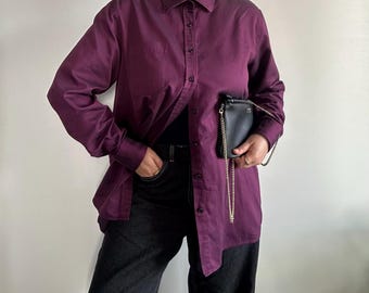 May include: A long-sleeved, purple button-down shirt with a black chain strap purse.