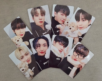 May include: Set of 8 photo cards featuring portraits of 8 different people. Each card has a white background and features a person holding a teddy bear. The people are all wearing casual clothing and have a variety of hairstyles.