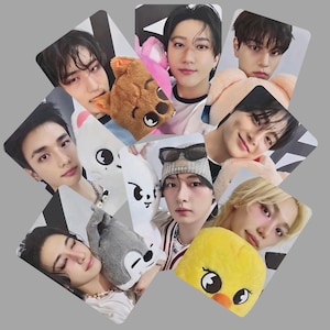May include: A collection of nine photo cards featuring young people, each holding a plush toy. The plush toys include a brown bear, a white rabbit, a gray wolf, and a yellow duck. The cards are arranged on a gray background.