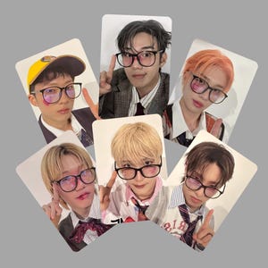 以下が含まれることがあります： 黒いフレームの眼鏡をかけた若い人々が写っている、長方形の写真カードが6枚。各カードには、さまざまな髪の色とスタイルで、手のジェスチャーでポーズをとっている異なる人物が写っています。カードは灰色の背景に配置されています。