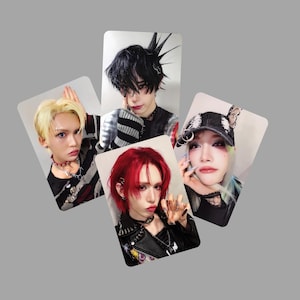 May include: Four portrait-style cards featuring individuals with bold makeup and hairstyles. One has blonde hair, another red, and a third with black hair. The fourth person has a black and white hat. Each person is wearing dark clothing and accessories.