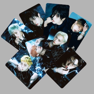Puede incluir: Una colección de siete tarjetas fotográficas rectangulares con retratos de personas con diversos colores de cabello, incluyendo rubio, negro y amarillo, sobre un fondo azul oscuro y melancólico con efectos de luz brillantes y joyas metálicas.