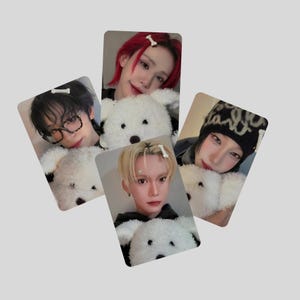 Puede incluir: Cuatro tarjetas fotográficas con individuos con diferentes peinados y accesorios, cada uno sosteniendo un oso de peluche blanco. Las tarjetas tienen un fondo gris claro. Los individuos tienen cabello rojo, rubio y negro.