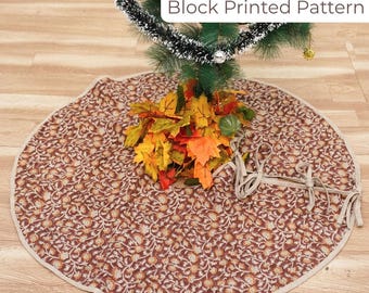 May include: A round Christmas tree skirt with a block printed pattern in brown and beige. The skirt has a beige border and is tied with beige ribbons. The text "Block Printed Pattern" is in a white box. The skirt is under a Christmas tree.