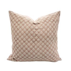 May include: A square decorative pillow with a repeating fleur-de-lis pattern in shades of beige and brown. The pillow has a soft, textured appearance and is designed for home decor.