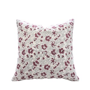 May include: Square decorative pillow with a floral pattern. The pillow features a cream-colored background with a repeating pattern of burgundy flowers and green leaves. The pillow is square-shaped and appears to be made of fabric.