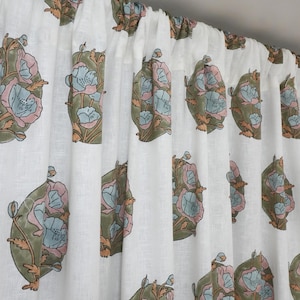 May include: White linen curtains with a repeating floral pattern. The design features large, stylized flowers in shades of pink, blue, green, and orange. The curtains are hanging from a rod, with soft folds.