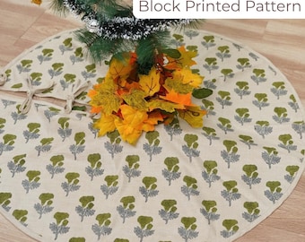 May include: A cream-colored Christmas tree skirt with a block-printed floral pattern in green and gray. The skirt is circular with a split for the tree trunk and tie closures. The text "Block Printed Pattern" is visible.