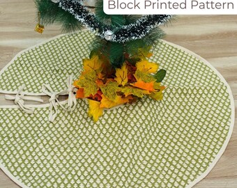 May include: A green and white block-printed Christmas tree skirt with a cream-colored border. The skirt is under a decorated Christmas tree with silver ornaments and a garland. The text "Block Printed Pattern" is visible.
