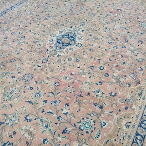 May include: A vintage rug with a floral pattern in shades of pink, blue, and green. The rug has a central medallion with a more intricate design.