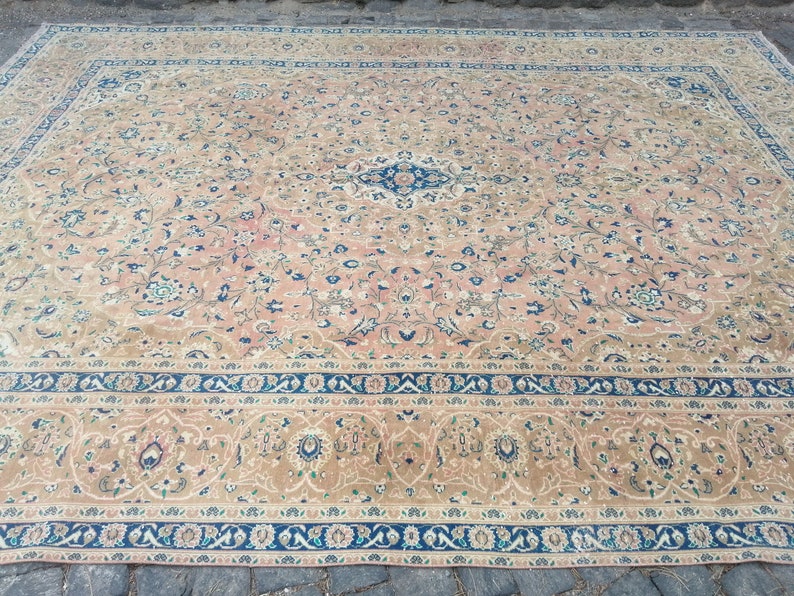 May include: A large, intricately patterned rug with a beige background and blue and green floral designs. The rug has a border with a repeating pattern of blue, white, and green.
