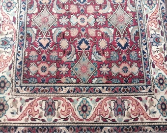 May include: A traditional Persian rug with a red, blue, and cream color scheme. The rug features intricate floral and geometric patterns.