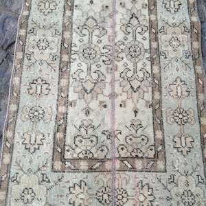 May include: A vintage Turkish rug with a light blue background and a brown and white floral pattern. The rug has a fringe border and is in good condition.