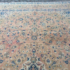 May include: A vintage Persian rug with a floral pattern in shades of pink, blue, and green. The rug has a central medallion and a border with intricate designs.