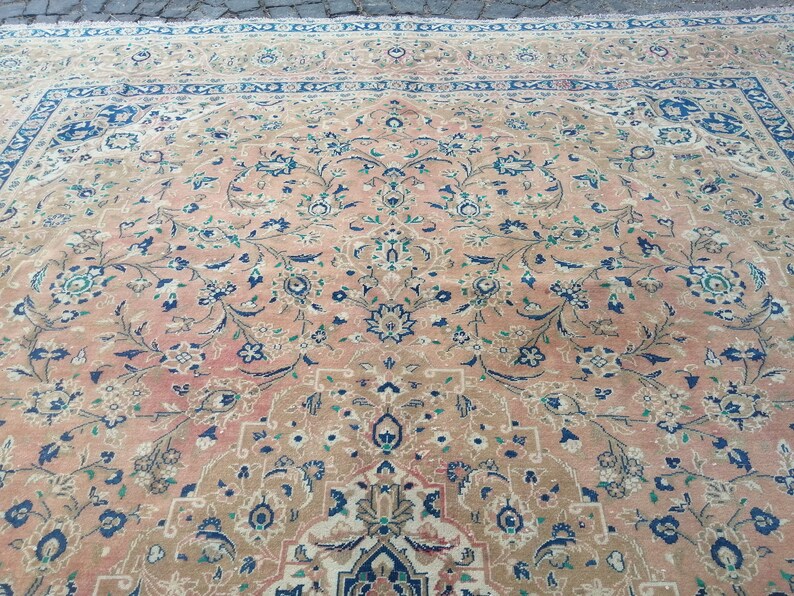 May include: A vintage Persian rug with a floral pattern in shades of pink, blue, and green. The rug has a central medallion and a border with intricate designs.