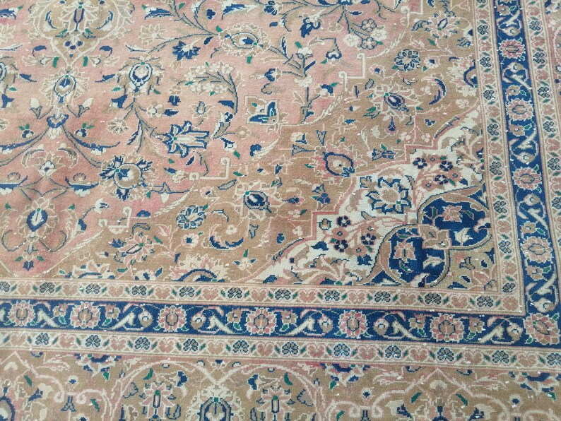 May include: A vintage rug with a floral pattern in shades of pink, blue, and beige. The rug has a detailed border with a repeating pattern.