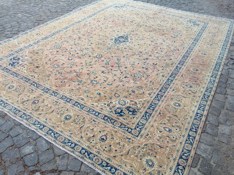 May include: A beige rug with a floral pattern and a blue border. The rug has a traditional Persian design.