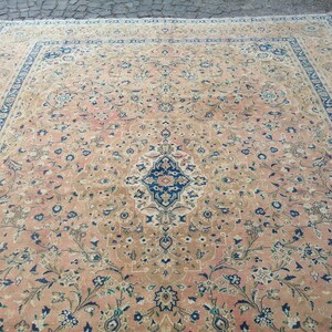May include: A large, rectangular rug with a floral pattern in shades of pink, beige, blue, and green. The rug has a central medallion with a geometric design.