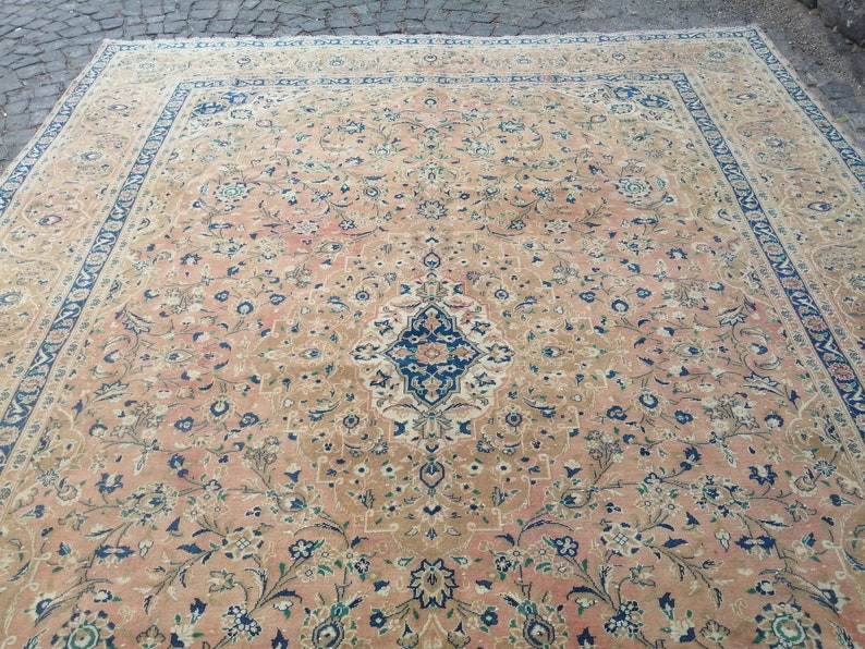 May include: A large, rectangular rug with a floral pattern in shades of pink, beige, blue, and green. The rug has a central medallion with a geometric design.