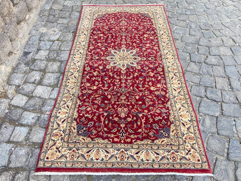 May include: A red rug with a floral pattern and a cream-colored border. The rug has a traditional Persian design.