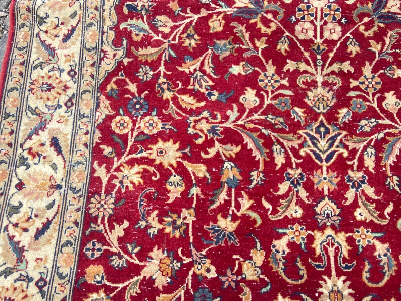 May include: A red rug with a floral pattern. The rug has a border with a cream and blue design.